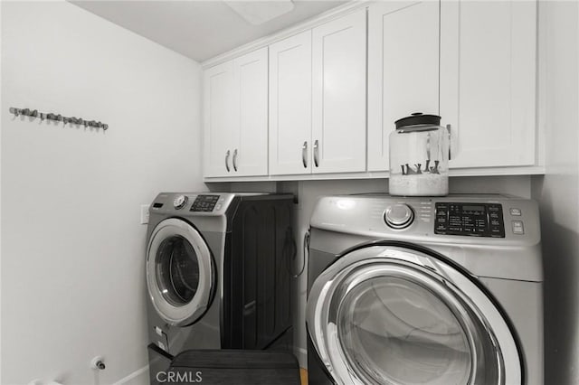 clothes washing area with washing machine and dryer, cabinet space, and baseboards