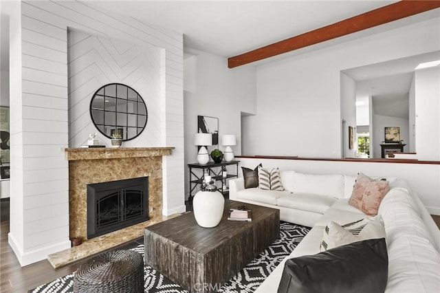 living room with vaulted ceiling with beams, wood finished floors, and a high end fireplace