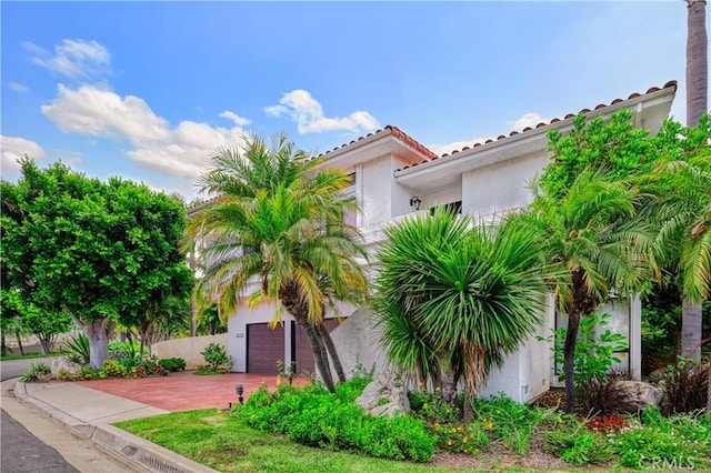 view of front of house with a garage, a tile roof, and stucco siding