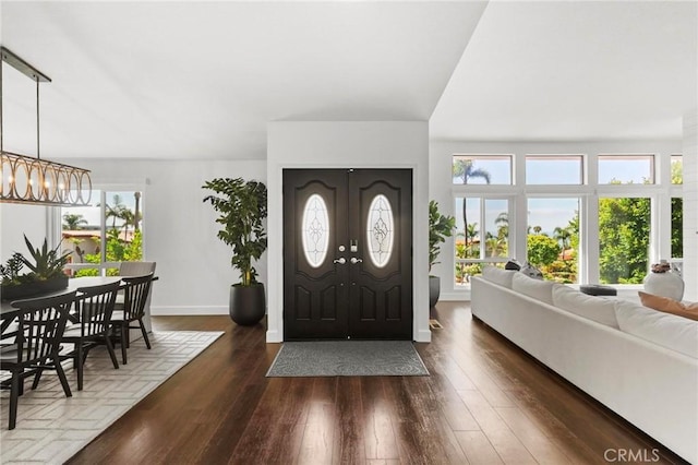 foyer entrance featuring a notable chandelier, baseboards, wood finished floors, and french doors