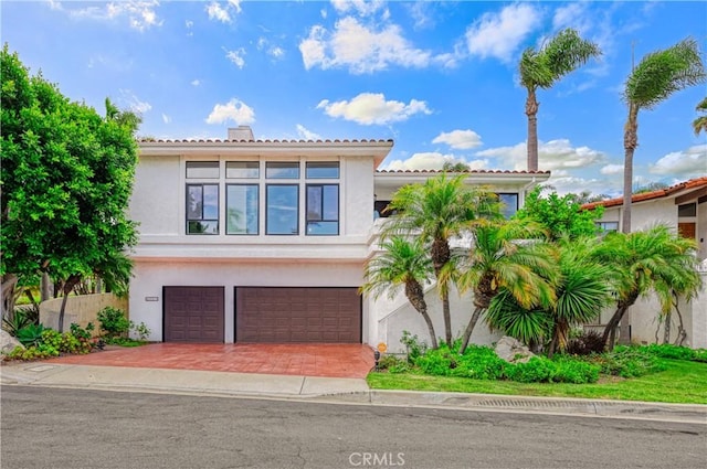 mediterranean / spanish house featuring a garage, decorative driveway, and stucco siding