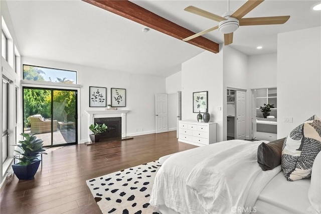 bedroom featuring wood finished floors, baseboards, access to exterior, beamed ceiling, and a glass covered fireplace