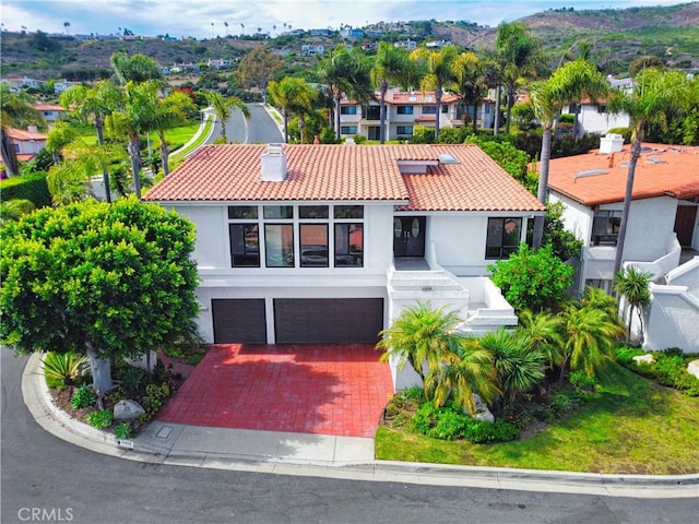 view of front facade with a garage, a tiled roof, decorative driveway, and stucco siding