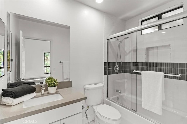 bathroom featuring toilet, vanity, and enclosed tub / shower combo