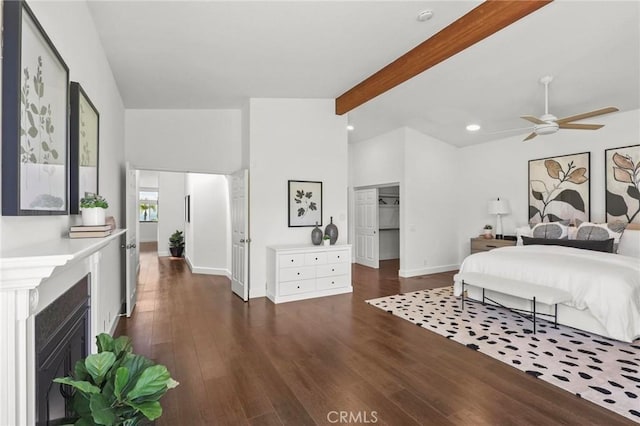 bedroom with vaulted ceiling with beams, dark wood-style floors, a fireplace with flush hearth, and baseboards