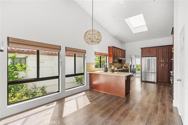 kitchen featuring a skylight, high quality fridge, dark wood-style flooring, a peninsula, and light countertops