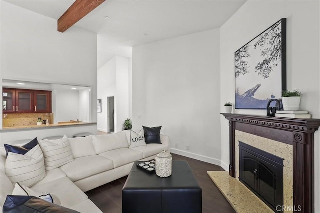 living area featuring baseboards, beamed ceiling, a premium fireplace, and dark wood-style flooring