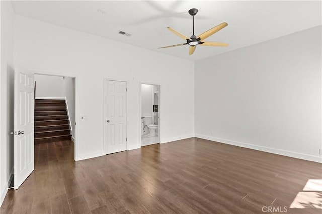 unfurnished bedroom with a spacious closet, dark wood-type flooring, visible vents, and baseboards