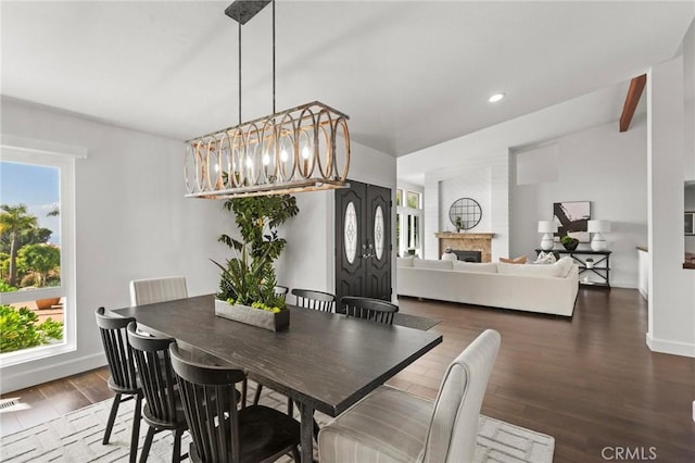 dining area with dark wood-style floors, plenty of natural light, a fireplace, and baseboards