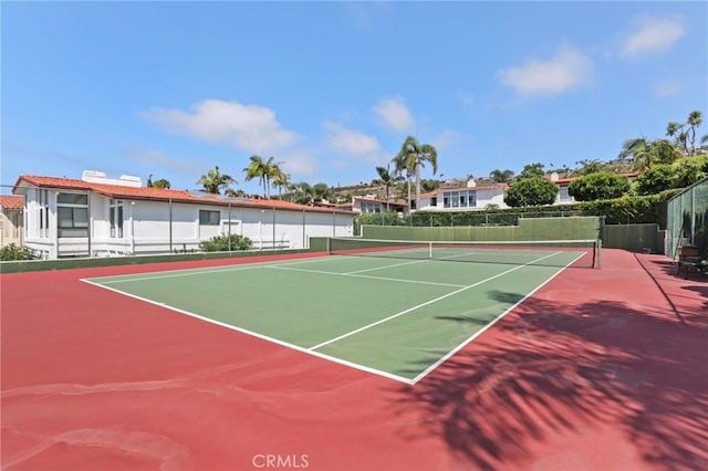 view of tennis court featuring community basketball court and fence