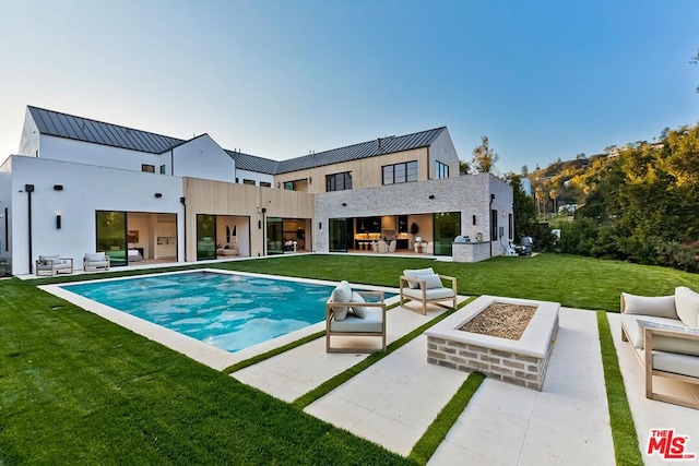 rear view of property with an outdoor kitchen, an outdoor living space with a fire pit, a patio area, and a yard