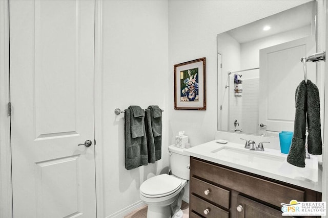 bathroom featuring toilet, vanity, and a shower