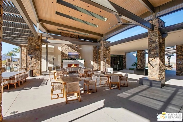 view of patio with ceiling fan and an outdoor stone fireplace