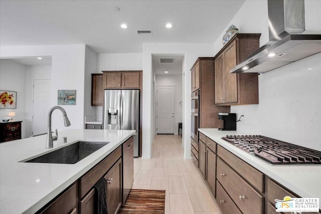 kitchen featuring stainless steel appliances, wall chimney exhaust hood, backsplash, and sink