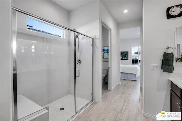 bathroom with toilet, vanity, and a shower with door