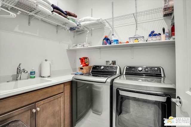 clothes washing area with cabinets, sink, and washer and clothes dryer