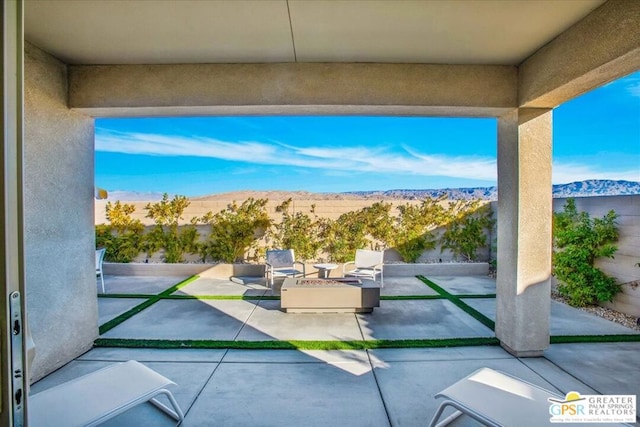 view of patio with a mountain view and a fire pit