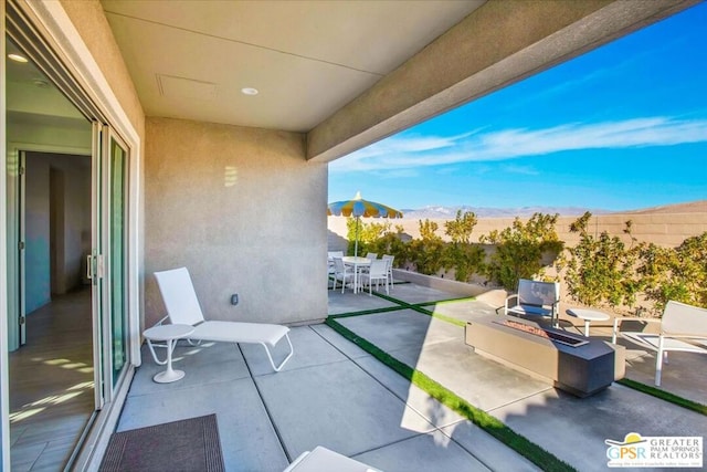 view of patio / terrace with a mountain view and a fire pit