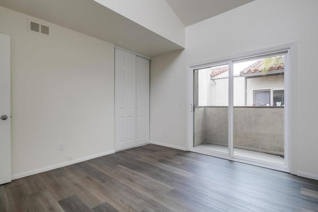 empty room with vaulted ceiling and dark hardwood / wood-style floors