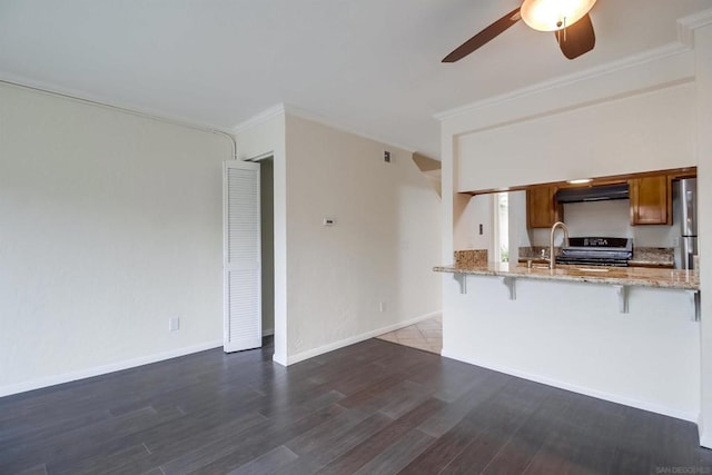 kitchen featuring extractor fan, a kitchen breakfast bar, kitchen peninsula, range with electric stovetop, and light stone counters