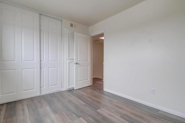 unfurnished bedroom with light wood-type flooring and a closet