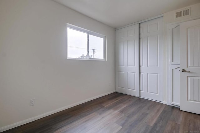 unfurnished bedroom featuring dark wood-type flooring and a closet