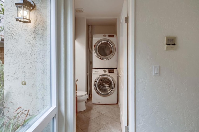 washroom with stacked washer and dryer and light tile patterned flooring