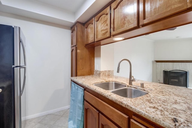 kitchen with dishwasher, stainless steel fridge, sink, and light stone counters