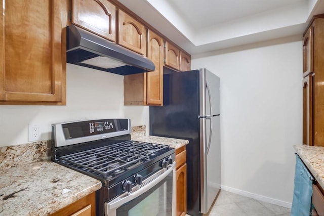 kitchen with light tile patterned floors, light stone countertops, and stainless steel appliances