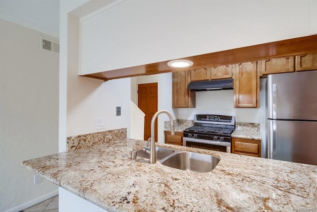 kitchen featuring light stone countertops, stainless steel appliances, sink, kitchen peninsula, and light tile patterned floors