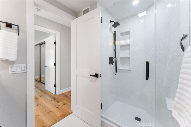 bathroom with a shower with door and hardwood / wood-style floors