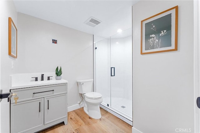 bathroom with toilet, wood-type flooring, an enclosed shower, and vanity