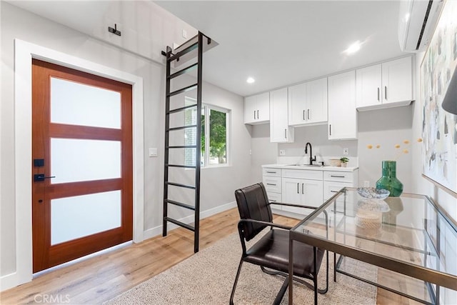 office area featuring a wall unit AC, light hardwood / wood-style floors, and sink