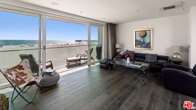 living room with a water view, floor to ceiling windows, a view of the beach, and hardwood / wood-style flooring