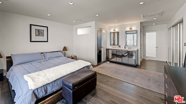 bedroom with a closet, dark hardwood / wood-style flooring, and ensuite bath