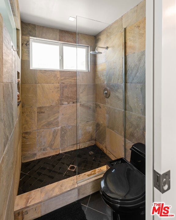 bathroom with tile patterned flooring and a tile shower