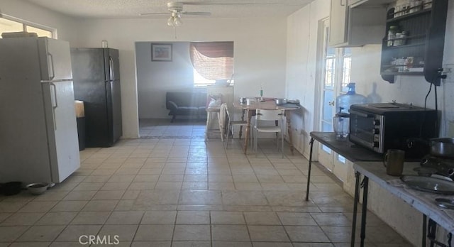 kitchen featuring white fridge, ceiling fan, white cabinets, and black refrigerator