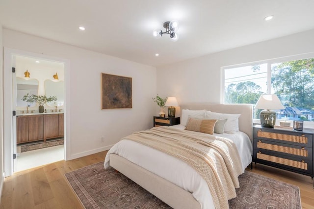 bedroom with ensuite bathroom and light hardwood / wood-style flooring