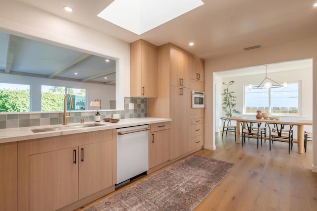 kitchen with dishwasher, sink, light brown cabinetry, and decorative backsplash