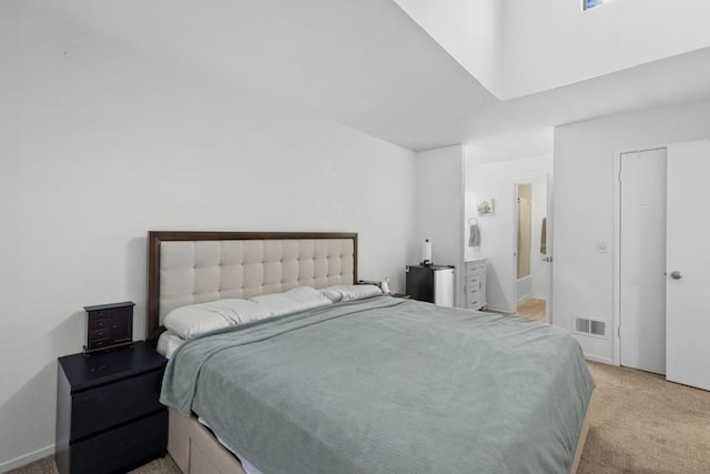 bedroom featuring ensuite bathroom and light colored carpet