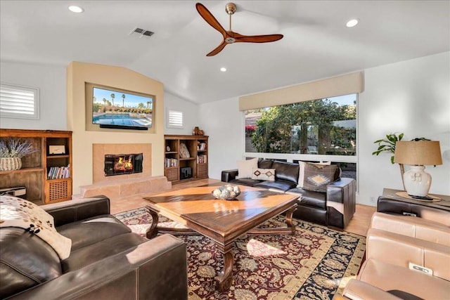 living room with ceiling fan, lofted ceiling, and a fireplace