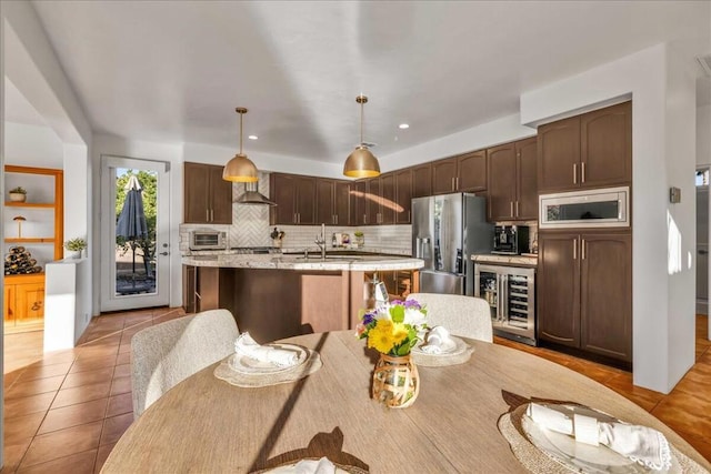 kitchen featuring wine cooler, sink, hanging light fixtures, a center island with sink, and stainless steel appliances