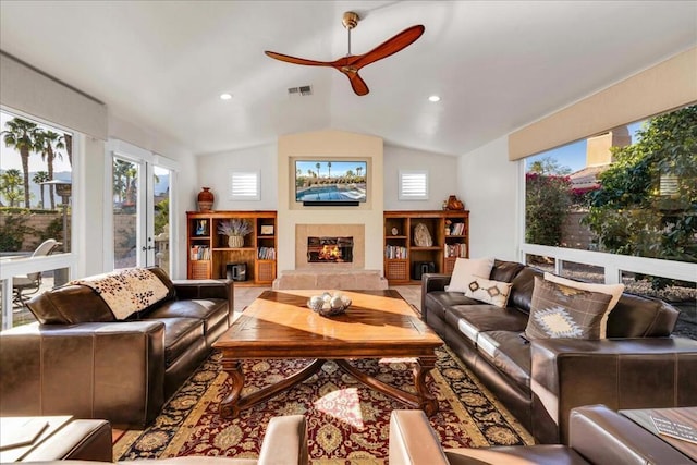 living room featuring a tiled fireplace, lofted ceiling, and ceiling fan