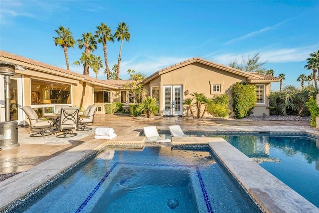 view of swimming pool featuring an in ground hot tub, a patio, and french doors