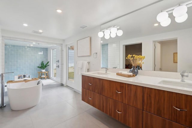 bathroom with a tub to relax in, vanity, and tile patterned flooring