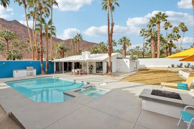 view of swimming pool with a mountain view, a patio area, an in ground hot tub, and an outdoor kitchen