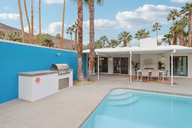 view of pool with a mountain view, an outdoor kitchen, grilling area, and a patio