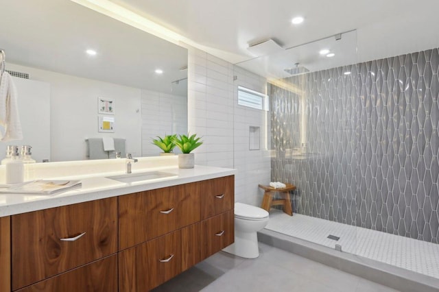 bathroom with tile patterned floors, vanity, tile walls, toilet, and walk in shower