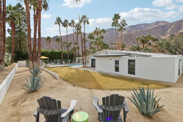 rear view of property with a mountain view and a lawn