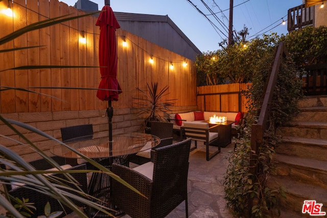 patio terrace at dusk featuring an outdoor living space with a fire pit